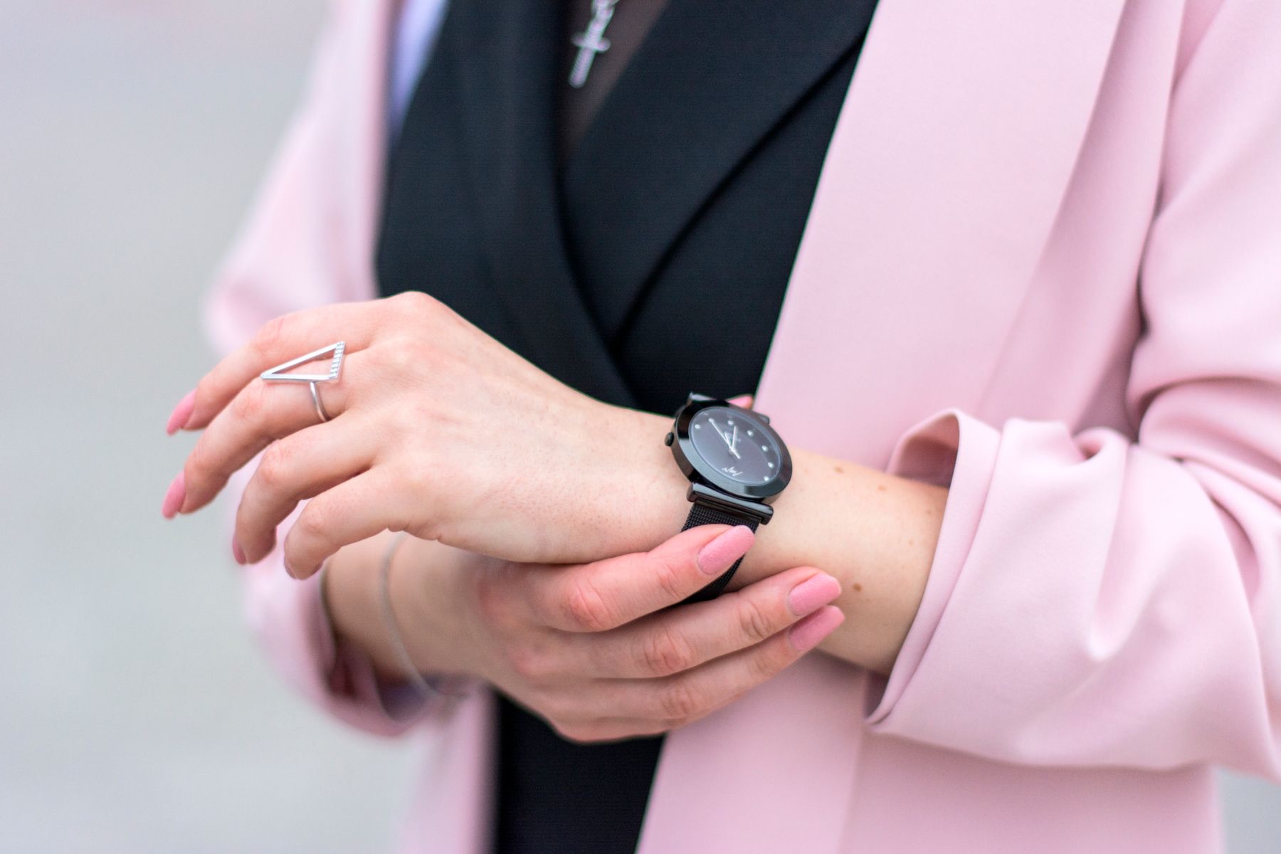 Minimal black wristwatch styled with a pink blazer and jewelry