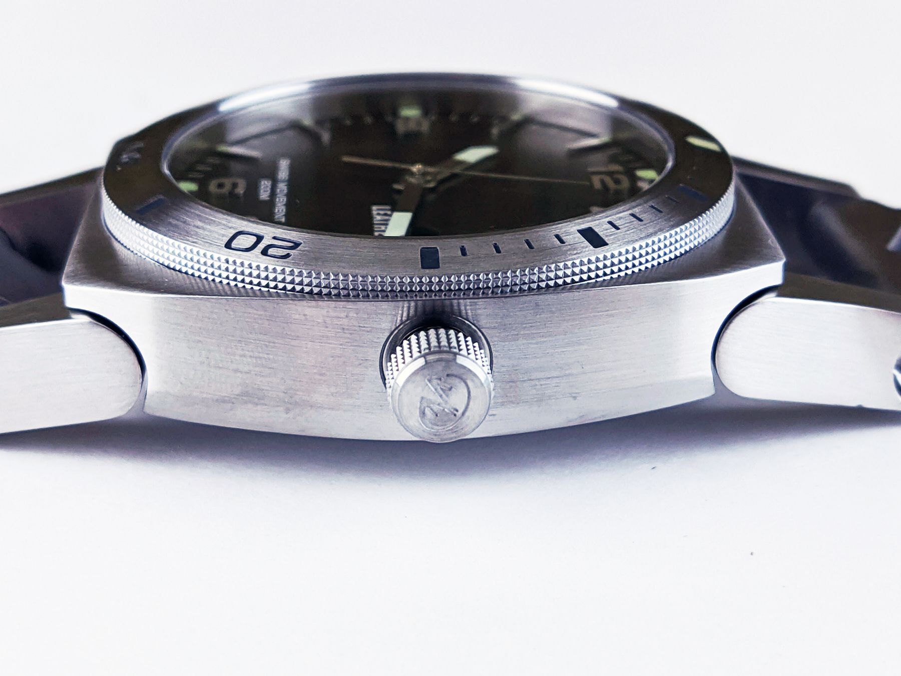 Detailed close-up of a stainless-steel wristwatch dial, bezel and crown