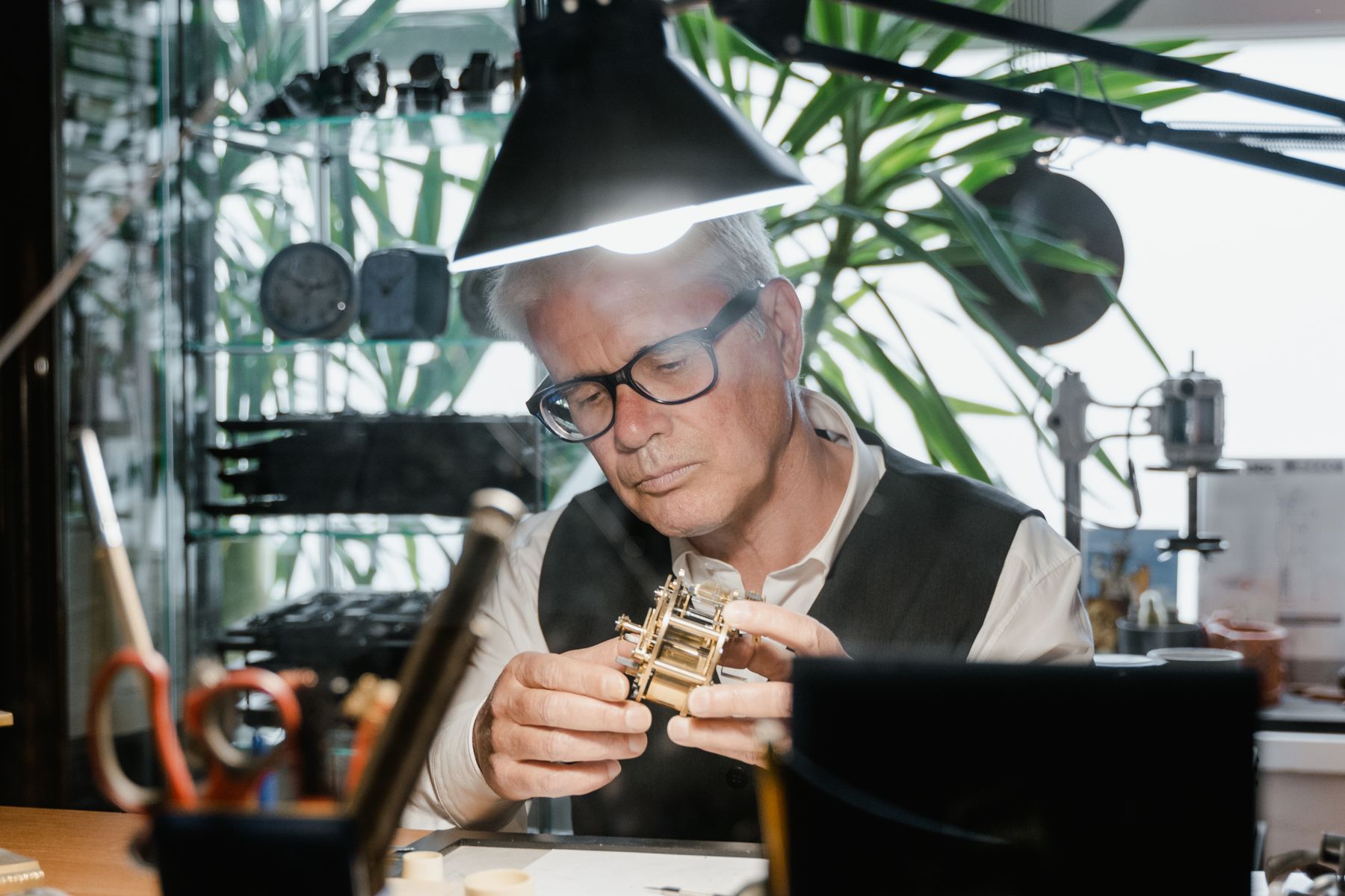 Watchmaker examining a mechanical timepiece at a workbench